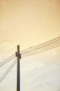 Low angle view of electricity pylon against sky during sunset