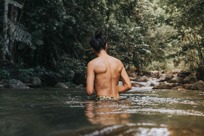 Rear view of shirtless man in forest