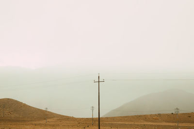 Electricity pylon on land against sky