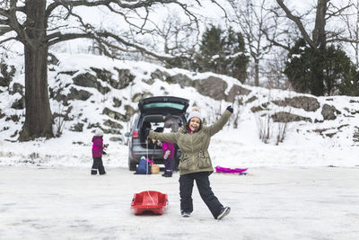 Full length of children on snow covered tree