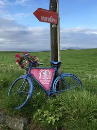 Bicycle sign on field against sky