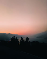 Silhouette people on mountain against sky during sunset