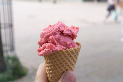 A waffle with a scoop of strawberry ice cream in hand