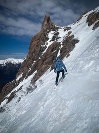Full length of man climbing snowcapped mountain against sky