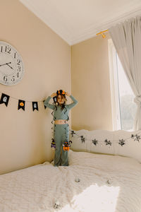 Rear view of woman standing on bed at home