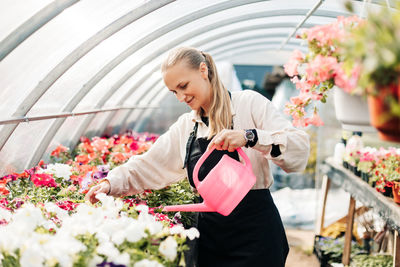 Professional girl gardener grows flowers in a greenhouse. daily care of plants. garden center