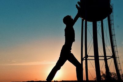 Low angle view of silhouette man standing against sky during sunset