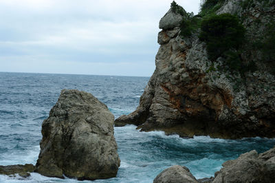 Rocks on sea shore against sky