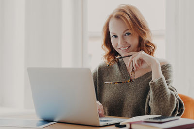 Businesswoman using laptop at desk in office