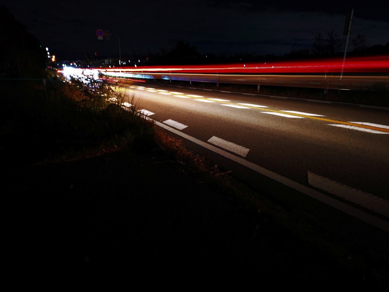 LIGHT TRAILS ON ROAD IN CITY AT NIGHT