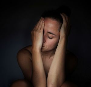 Portrait of young woman against black background