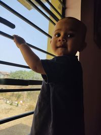 Portrait of cute boy looking through window