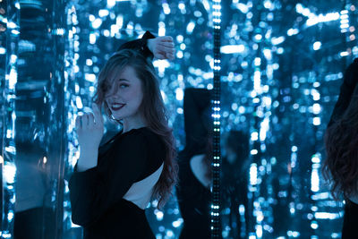 Portrait of young woman standing against illuminated lights