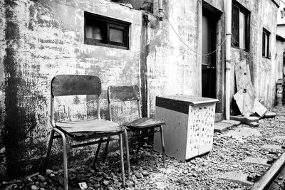 Old empty chairs by abandoned building