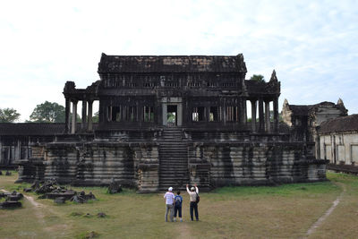 People at old ruins against sky