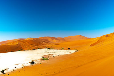 Scenic view of desert against clear blue sky