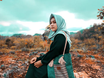 Side view of young woman standing on land against sky