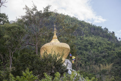 Rear view of temple amidst trees against sky