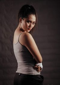 Portrait of woman standing against wall