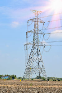 Low angle view of electricity pylon on field against sky