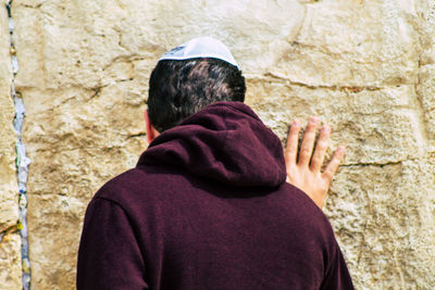 Rear view of people standing against wall