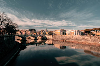 Bridge over river against sky in town