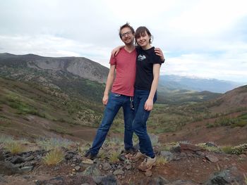 Portrait of couple standing on rock against sky