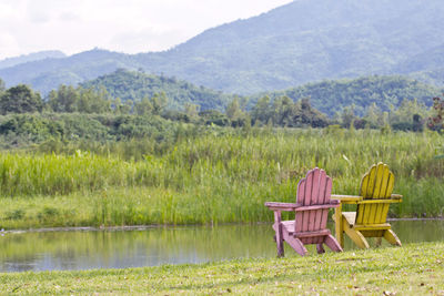 Chair on field by lake