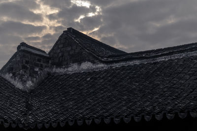 Low angle view of roof on old building against cloudy sky