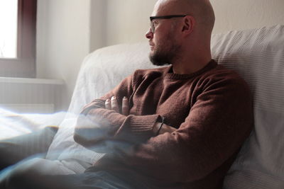 Thoughtful man relaxing on bed at home