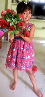 Cute girl holding red while standing on tiled floor