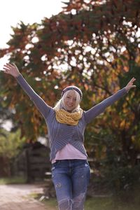 Young woman with arms outstretched standing against plants