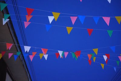 Low angle view of flags against clear blue sky