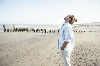 Man standing on beach against clear sky