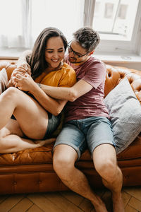 Happy couple sitting on sofa at home