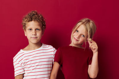 Portrait of sibling against red background
