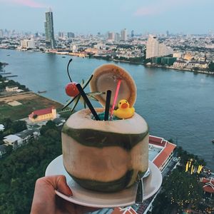 Close-up of hand holding ice cream against cityscape