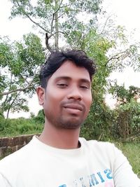 Portrait of young man standing against trees