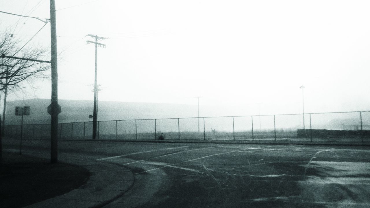 road, transportation, clear sky, road marking, street, copy space, street light, empty, the way forward, sky, electricity pylon, day, outdoors, no people, asphalt, power line, built structure, car, foggy