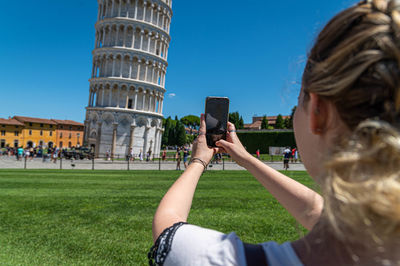 Rear view of woman photographing historical building