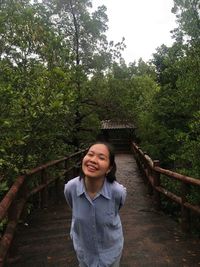 Portrait of smiling young woman standing against trees