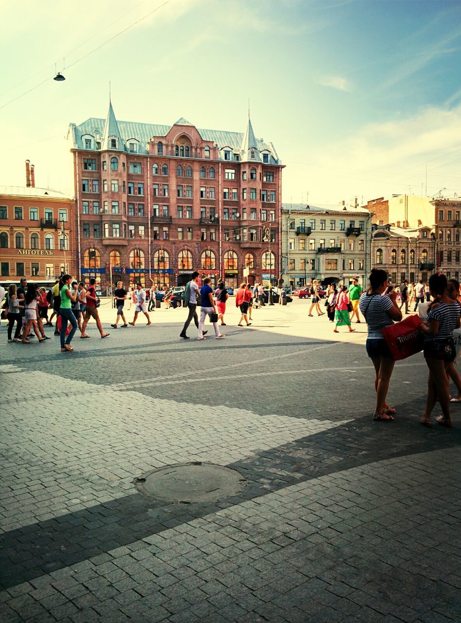 building exterior, large group of people, architecture, built structure, city, men, person, street, city life, walking, lifestyles, sky, leisure activity, city street, mixed age range, town square, road, day, crowd