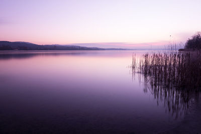 Scenic view of lake against clear sky at sunset