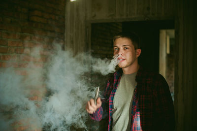 Portrait of young man smoking electronic cigarette