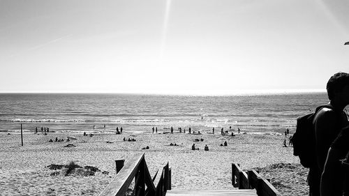 People standing on beach against clear sky