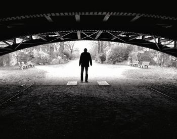 Rear view of silhouette man walking in tunnel