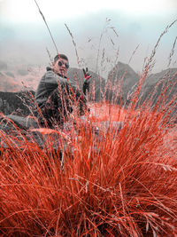 Man sitting on field against sky