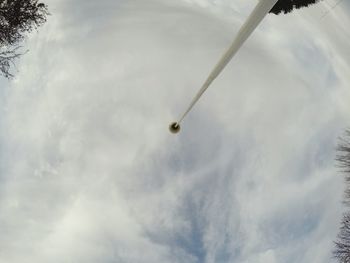 Low angle view of trees against cloudy sky