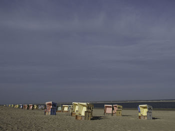 Hooded chairs on beach against sky