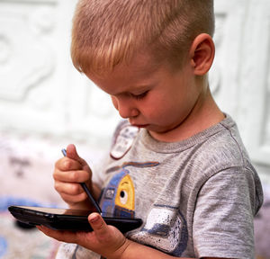 Close-up of boy using phone at home